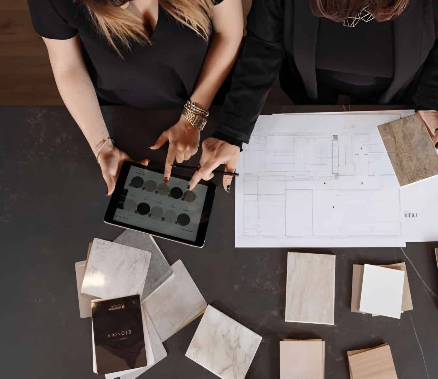 Two women in London looking at a tablet while laying out bespoke tiles.