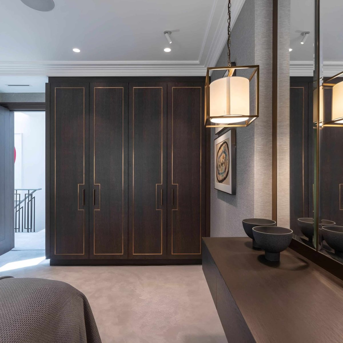 A bedroom in London with bespoke dark wood cabinets and a mirror from Mr Wardrobe.